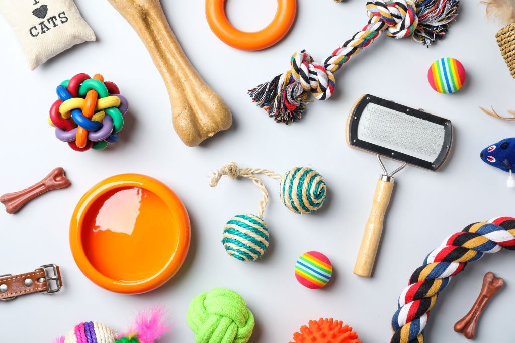Na imagem, vários brinquedos para pet espalhados por uma mesa. Tais como bolinhas, cordas, entre outros.