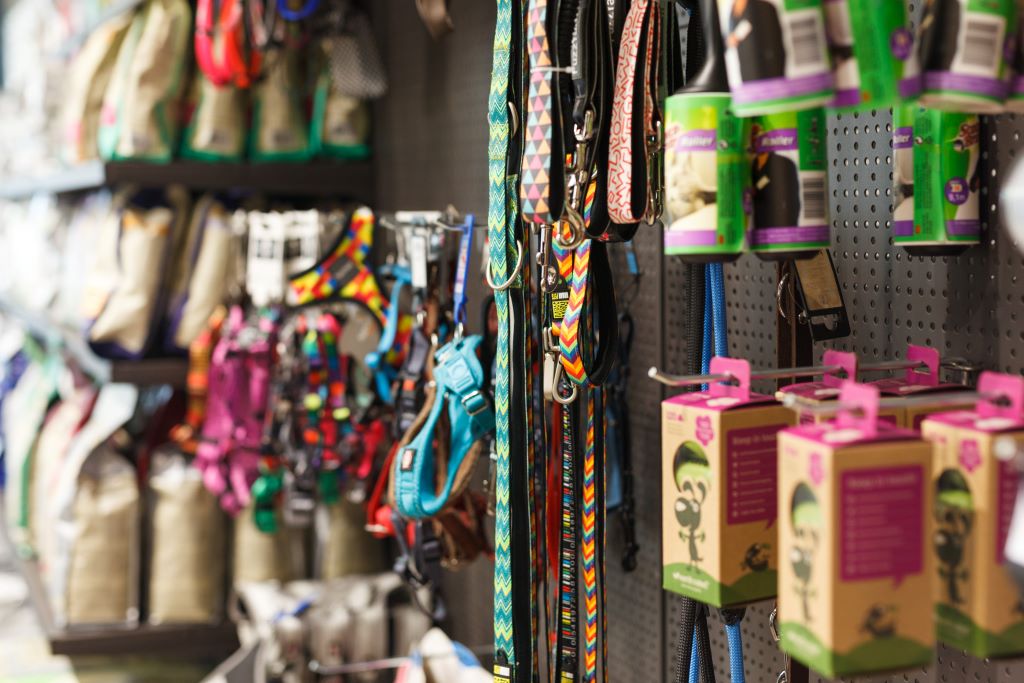 Na imagem a foto borrada de uma prateleira cheia de produtos de pet, como coleiras, brinquedos, entre outros.
